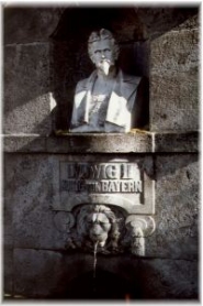 Die Büste Ludwigs II. (1845-1886) trägt die Inschrift: „Ludwig II König von Bayern“. Unter der Inschrift ist ein Wasser speiender bayerischer Löwe zu sehen. Quelle: Touristikinformation Grassau